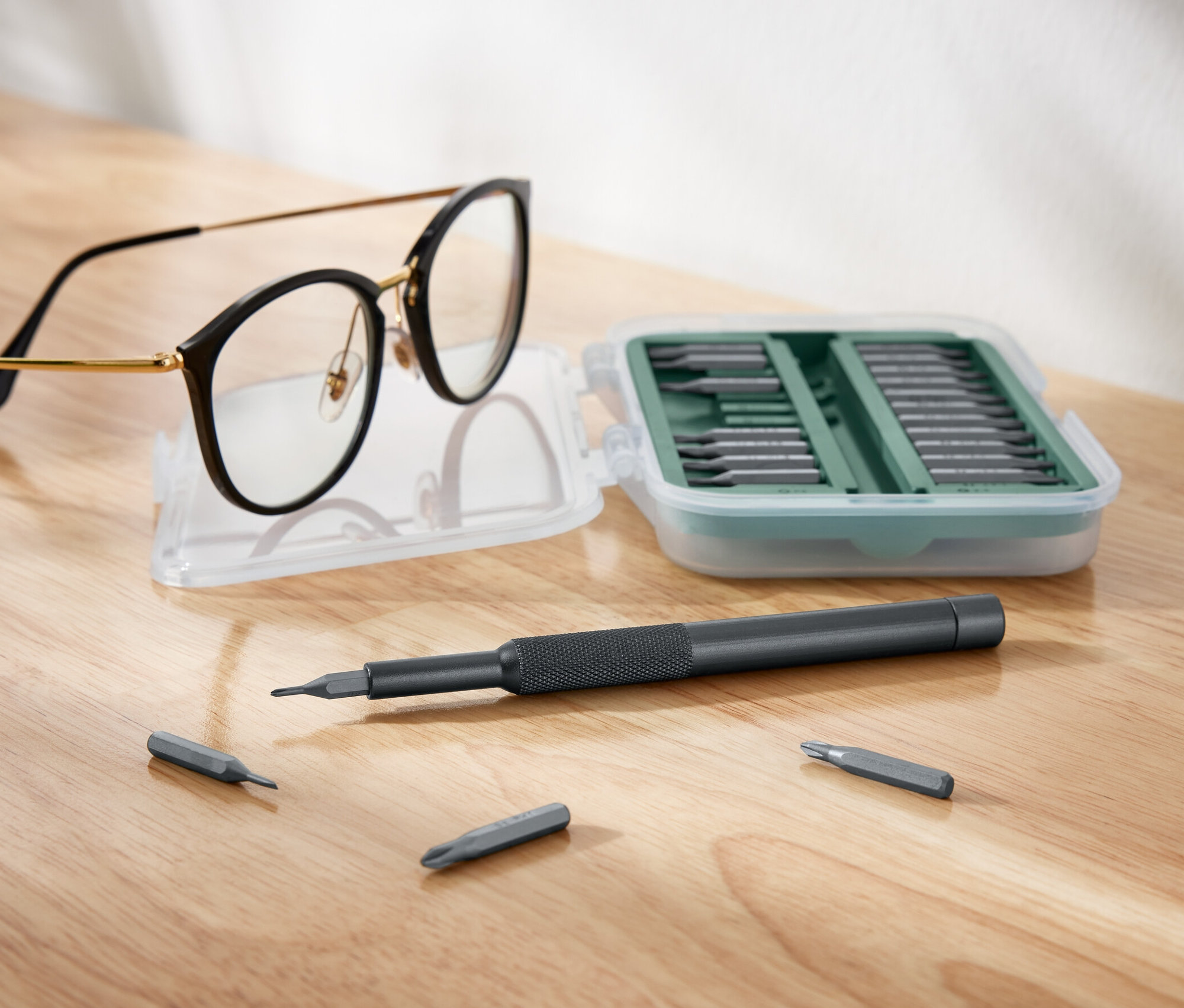 Des lunettes sont posées à côté d'un jeu de tournevis de précision ouvert.