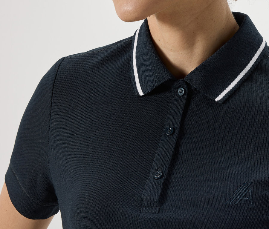 Gros plan sur un polo technique bleu foncé pour femme avec un liseré blanc sur le col.