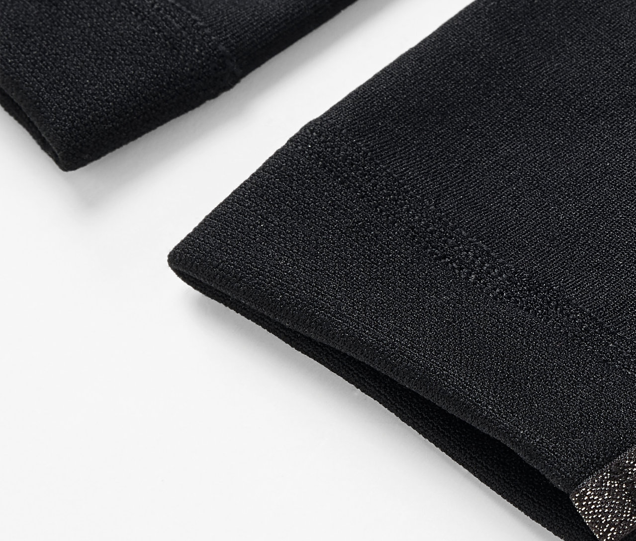 Gros plan de deux manchettes noires sur fond blanc.