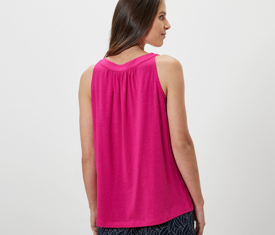 Femme regardant par-dessus son épaule portant un haut rose vif.