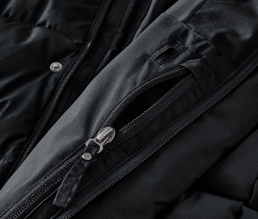 Gros plan sur une veste noire avec une fermeture éclair de poche ouverte.