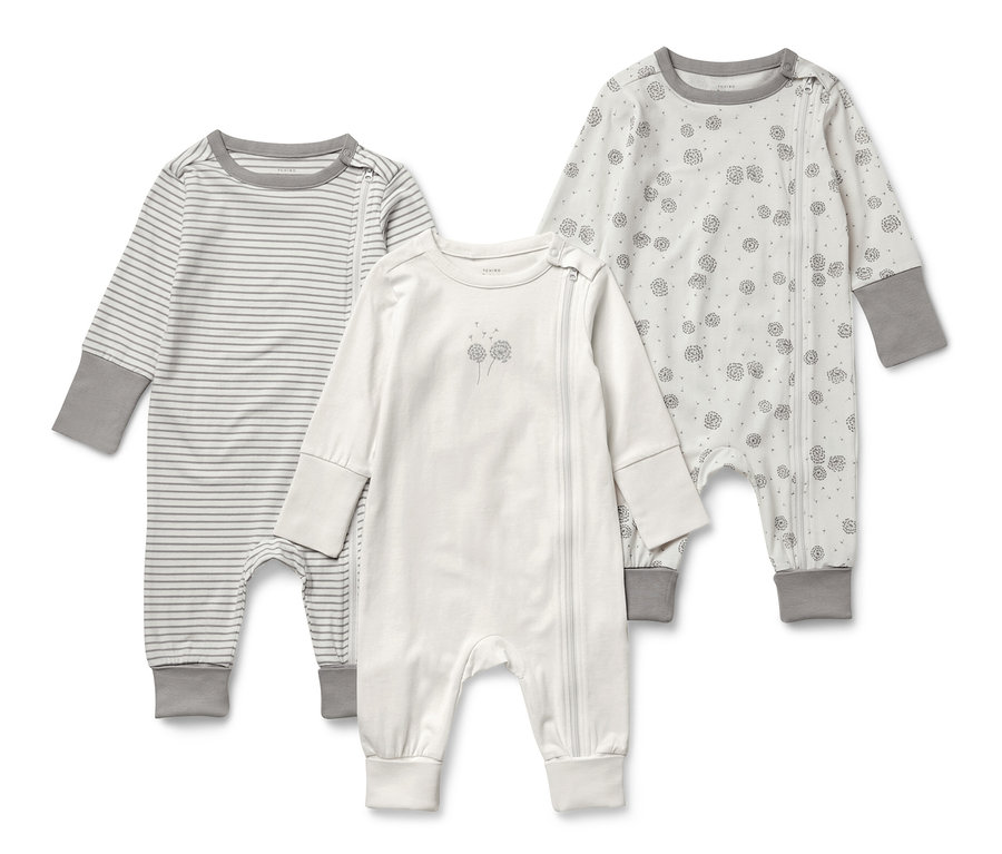 Trois pyjamas pour bébé à manches longues. Un rayé, un avec un imprimé floral et un blanc.