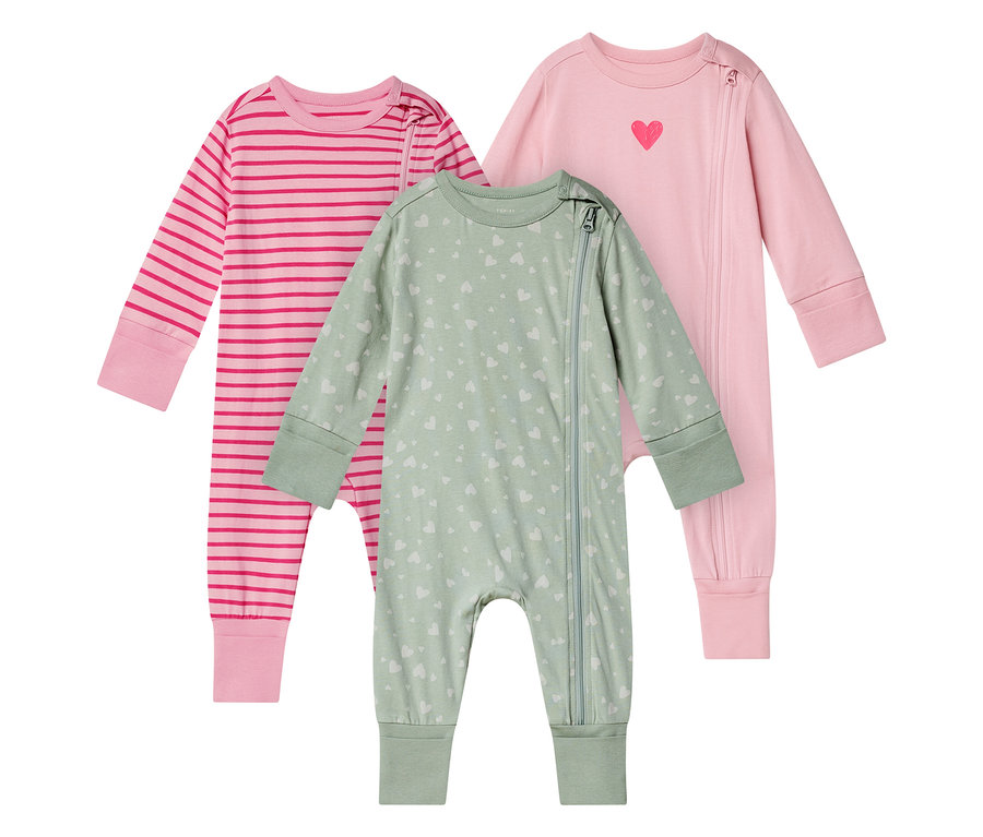 Trois pyjamas de bébé sont côte à côte : un rose rayé, un vert clair avec des cœurs et un rose avec un cœur.