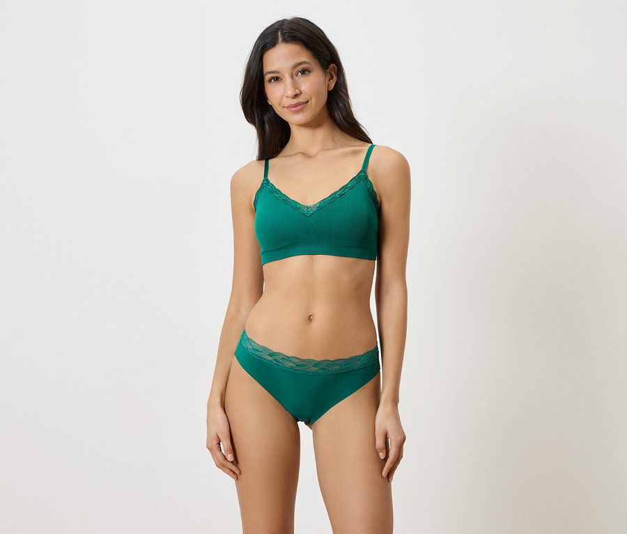 Femme portant un soutien-gorge et une culotte verts avec des finitions en dentelle.