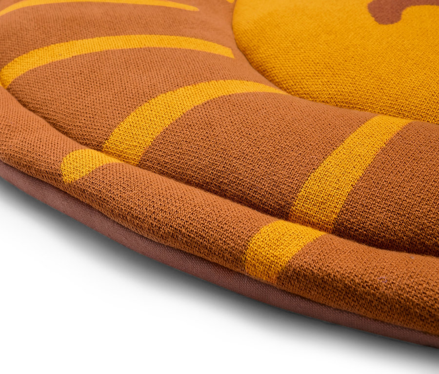 Gros plan d'un coussin rond marron avec des rayures jaunes.