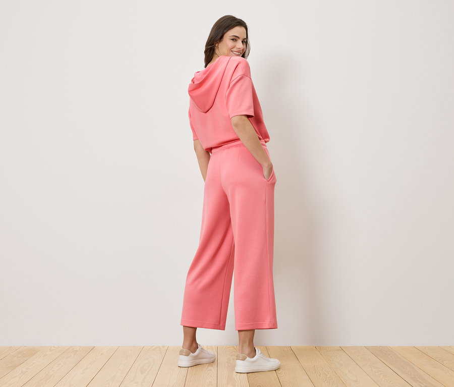 Femme regardant par-dessus son épaule portant un sweat à capuche rose et une culotte.