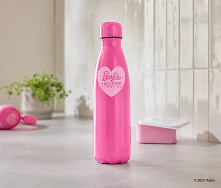 Une bouteille d'eau rose avec un logo Barbie est posée sur un comptoir de cuisine, à côté d'un casque audio et d'une boîte à lunch.