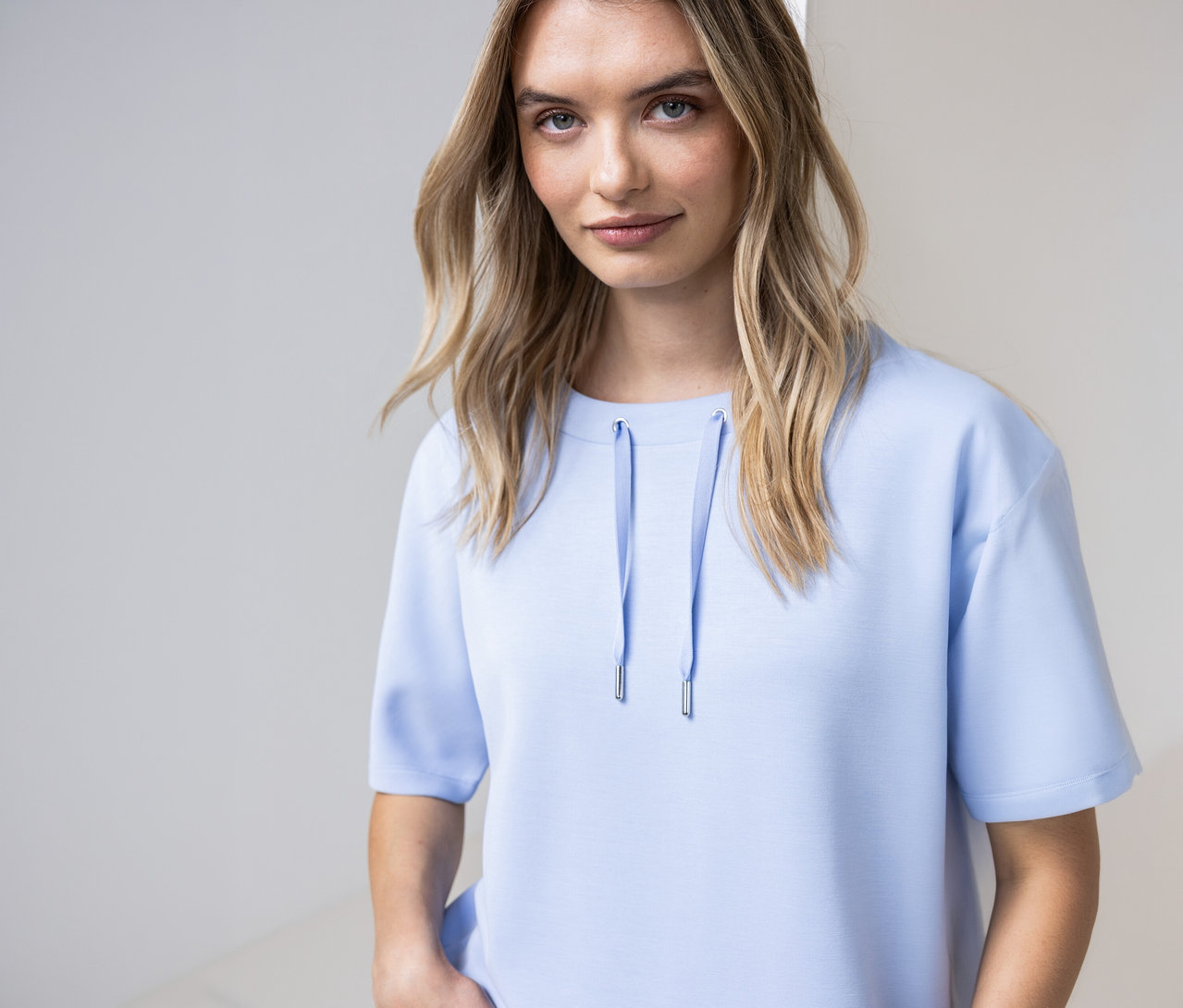 Une femme porte une chemise Street One bleu clair avec des cordons à l'encolure.