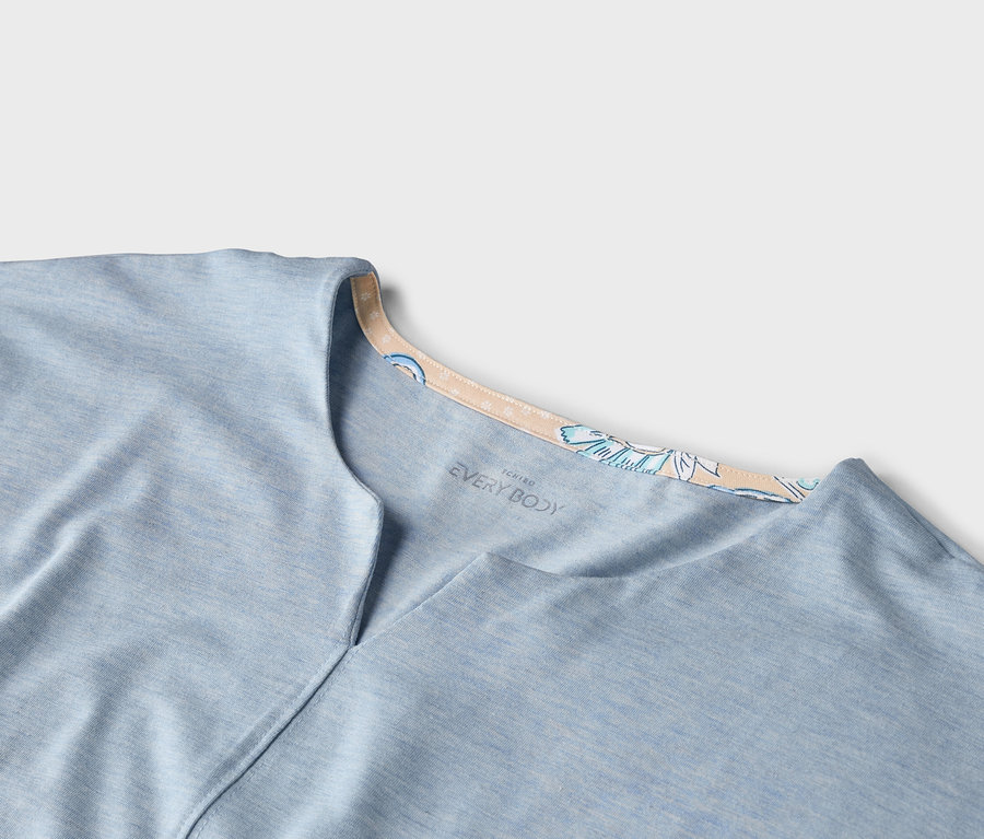 Gros plan d'un t-shirt bleu clair "EVERY BODY" avec un col en V et un col floral.