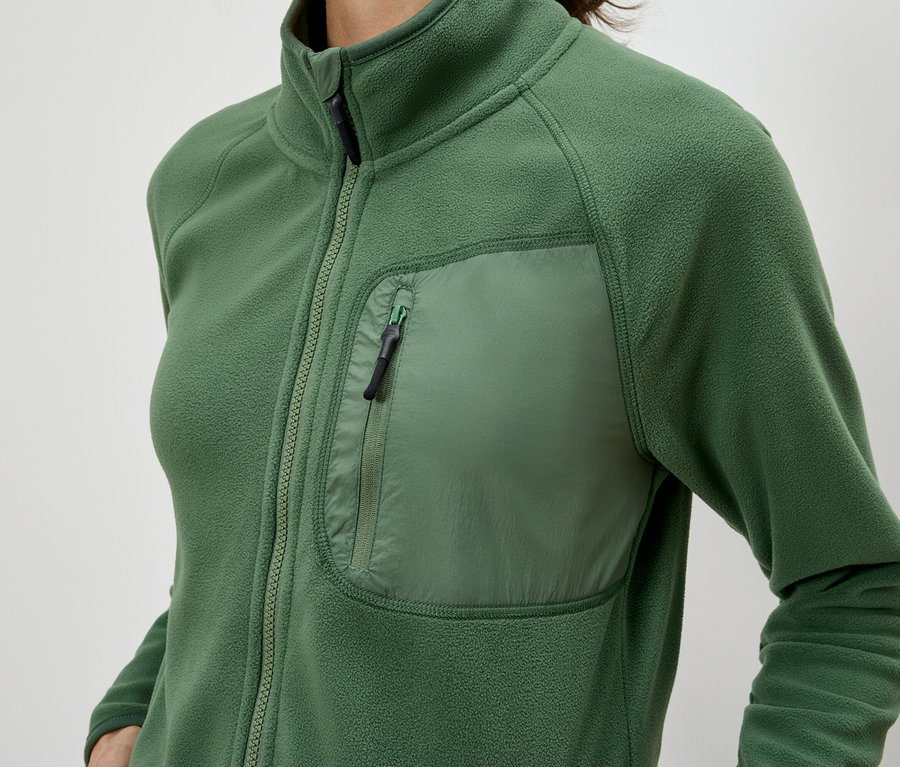 Gros plan d'une femme portant une veste en polaire verte zippée avec une poche poitrine.