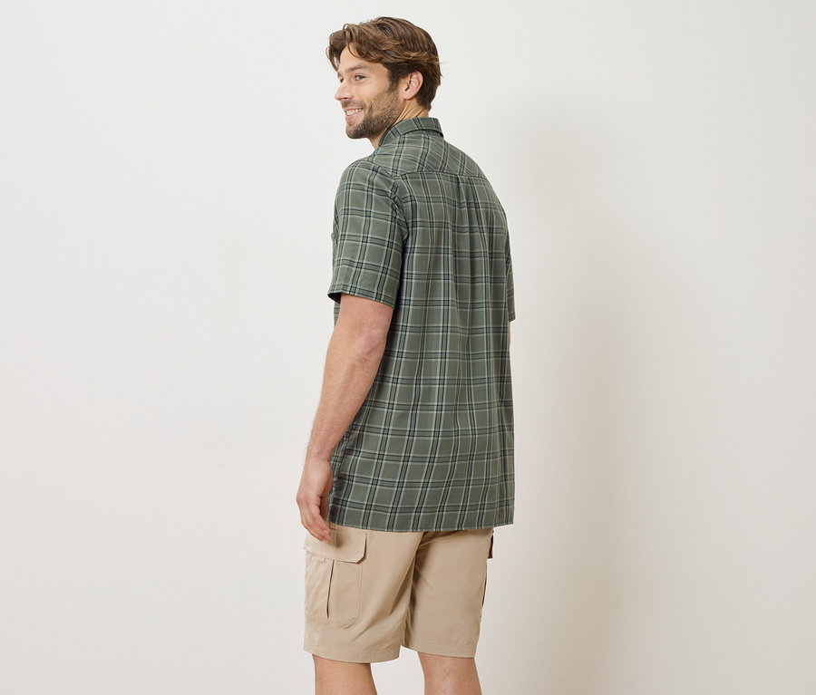 Homme vu de dos portant une chemise à carreaux à manches courtes et un short beige.