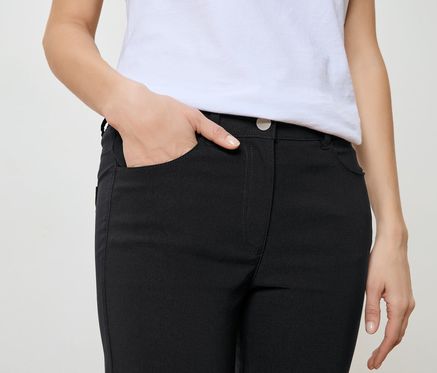 Femme avec la main dans la poche d'un pantalon noir et un t-shirt blanc.
