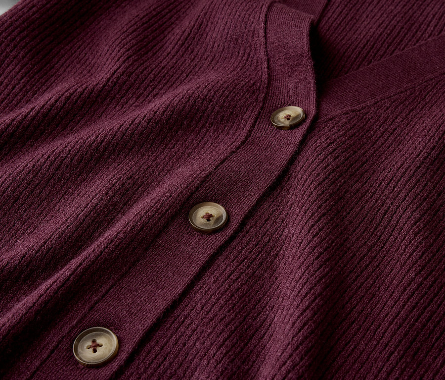 Gros plan sur un cardigan bordeaux avec trois boutons marron.