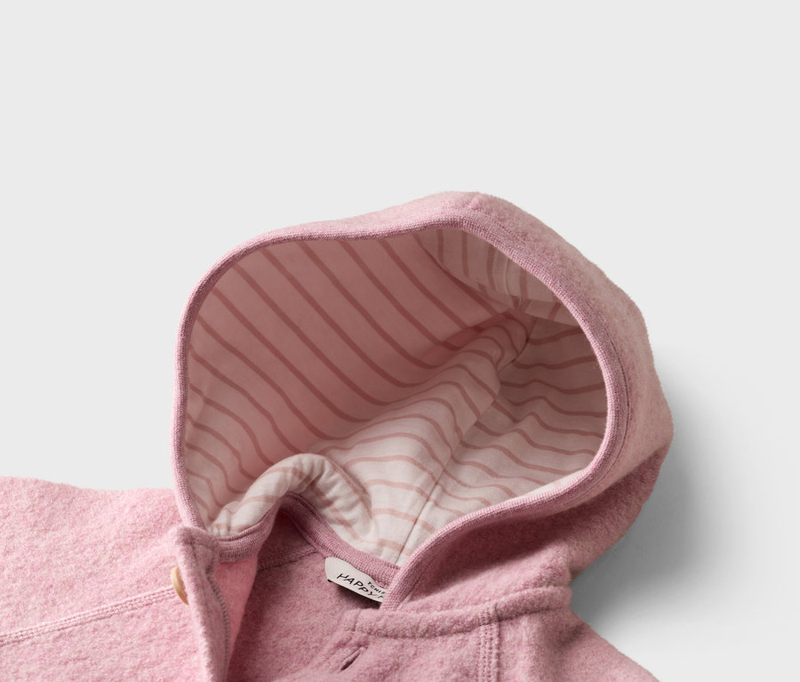 Gros plan sur une veste en laine rose avec une capuche à rayures roses et blanches à l'intérieur.