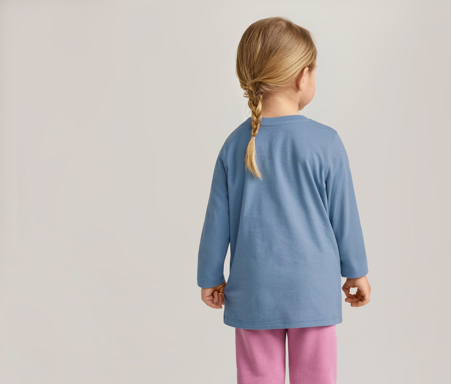 Vue de dos d'un enfant avec une tresse, portant un t-shirt bleu à manches longues et un pantalon rose.