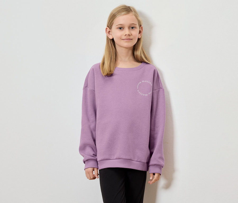 Fille aux cheveux blonds portant un sweat-shirt violet avec l'inscription "nonstop motion".