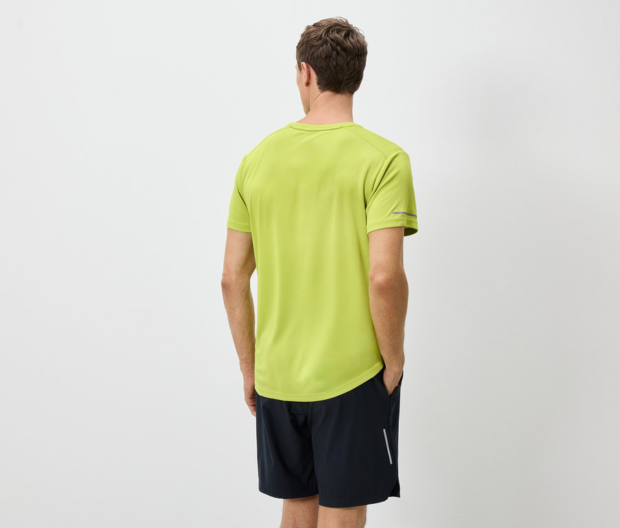 Vue arrière d'un homme portant un t-shirt vert clair et un short noir sur fond blanc.