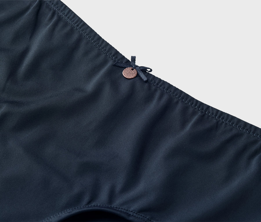 Gros plan de sous-vêtements bleu marine avec un nœud et un petit bouton.