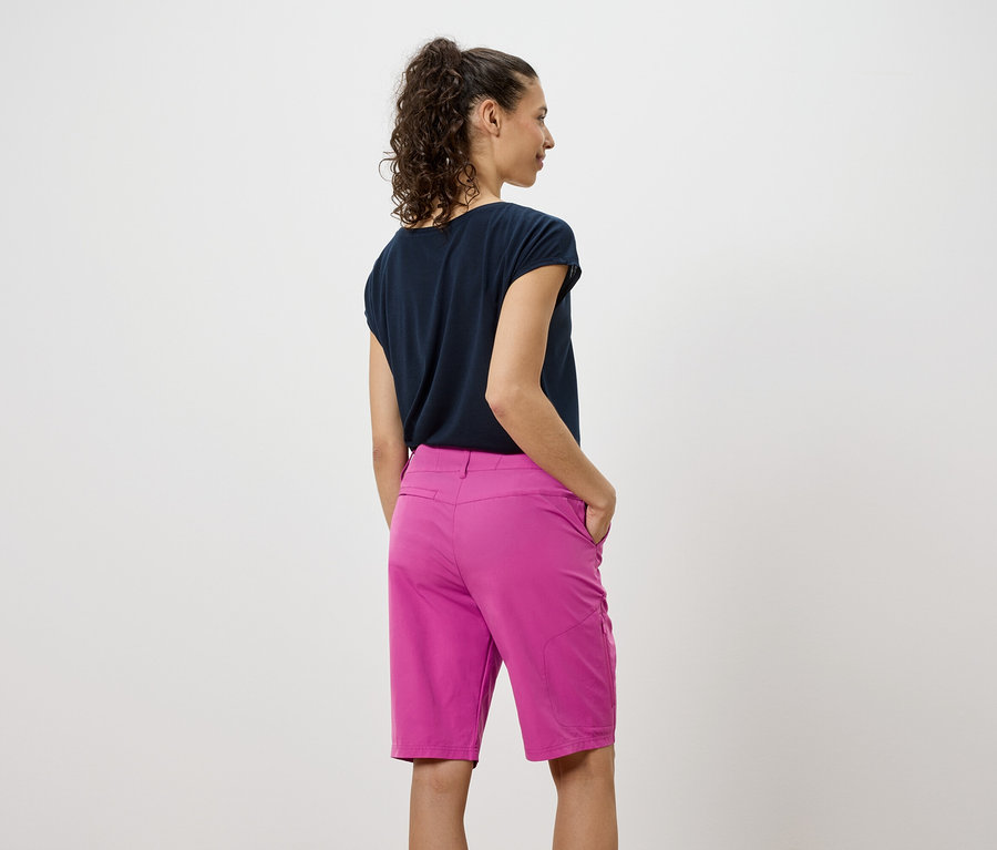 Vue arrière d'une femme portant un t-shirt foncé et un short rose.