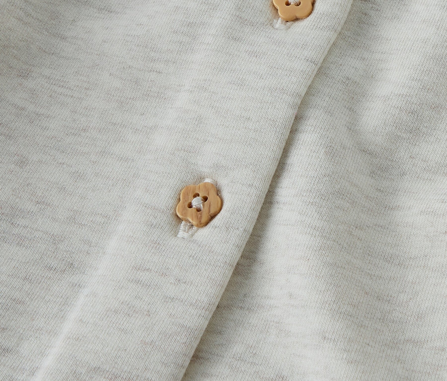 Gros plan d'un tissu gris clair avec trois boutons en forme de fleur.