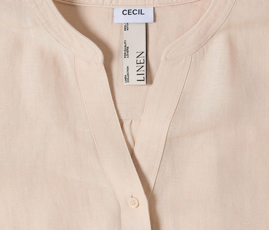 Gros plan d'une chemise claire en lin avec bouton et étiquette CECIL.