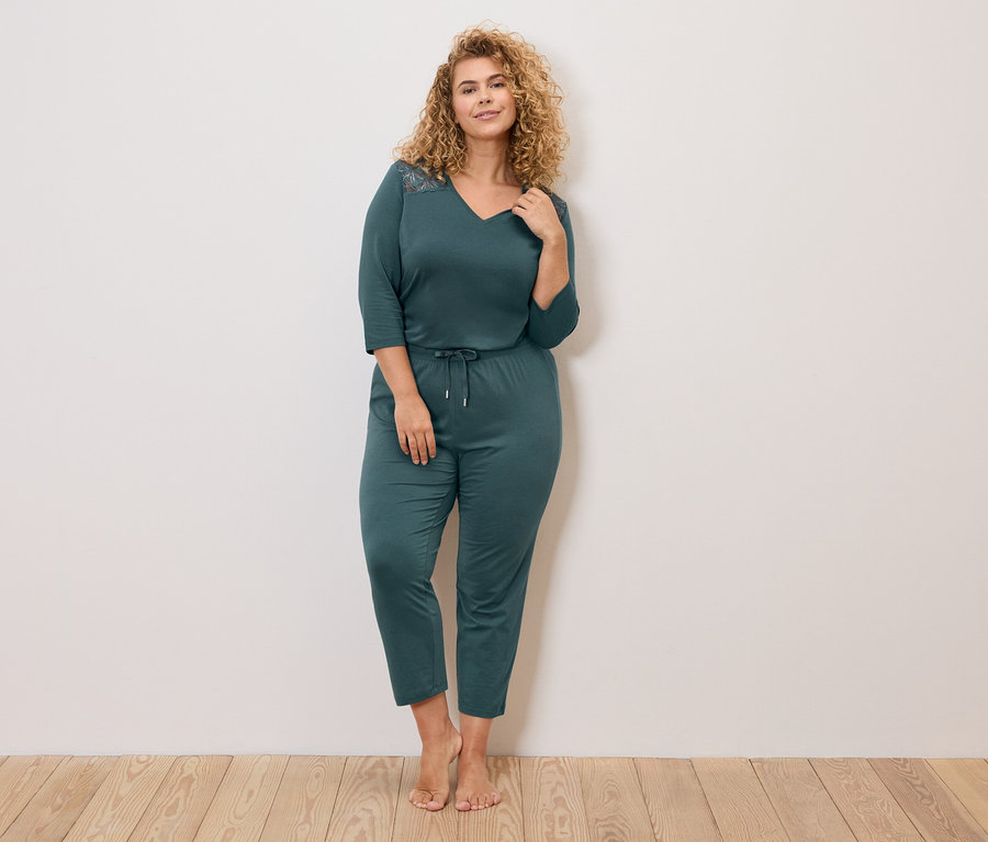 Femme aux cheveux bouclés portant un pyjama bleu marine à manches longues et cordon de serrage à la taille.