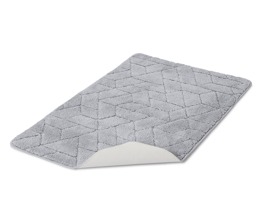 Un tapis de bain gris avec un motif géométrique posé sur un fond blanc.