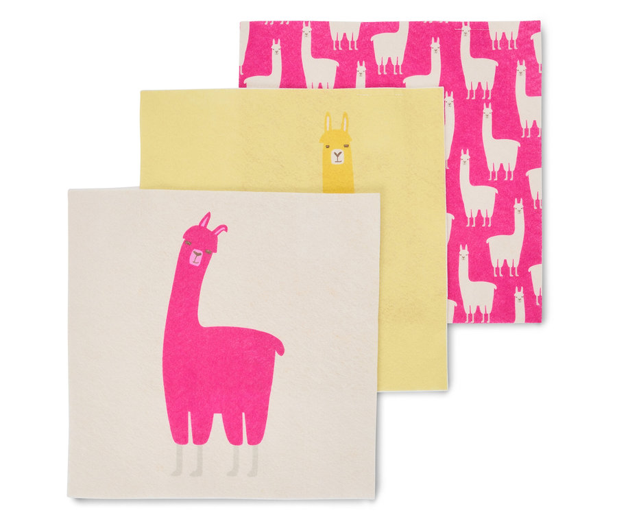 Trois serviettes sont superposées : une blanche avec un lama rose, une jaune avec un lama jaune et une rose avec des lamas blancs.