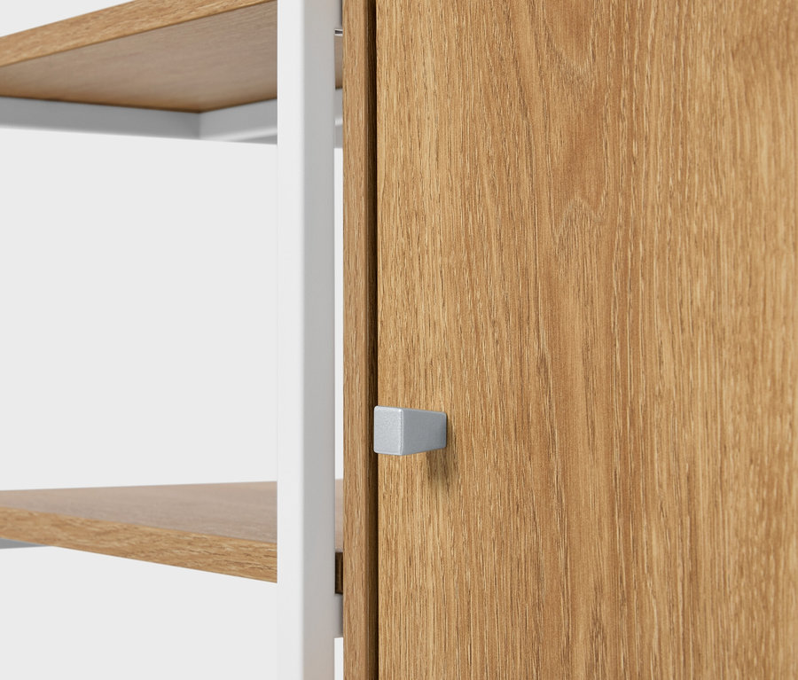Gros plan d'une étagère avec des tablettes en bois et une porte en bois avec une poignée argentée carrée.