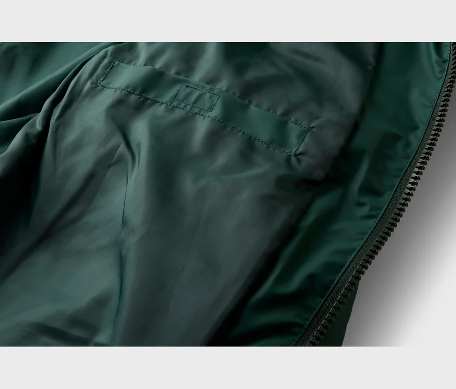 Intérieur d'une veste vert foncé, avec une poche intérieure cousue et une fermeture éclair sur le côté droit.