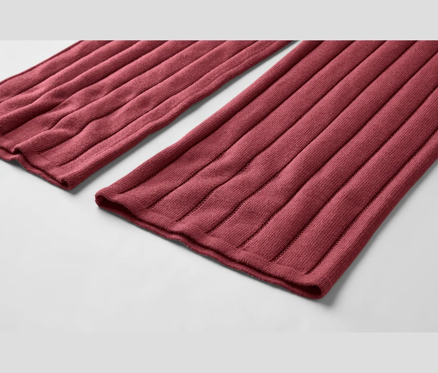 Deux morceaux de tissu tricoté côtelé rouge foncé, posés à plat sur une surface gris clair, montrant des côtes verticales prononcées.