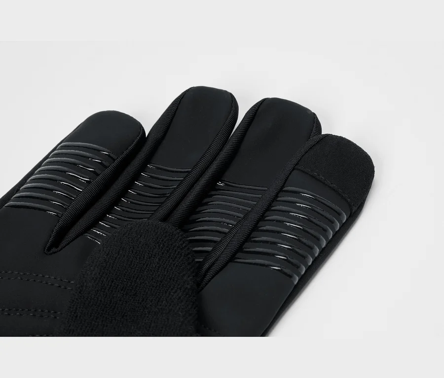 Gros plan d'un gant noir avec des bandes antidérapantes sur les doigts et un tissu doux sur le pouce.