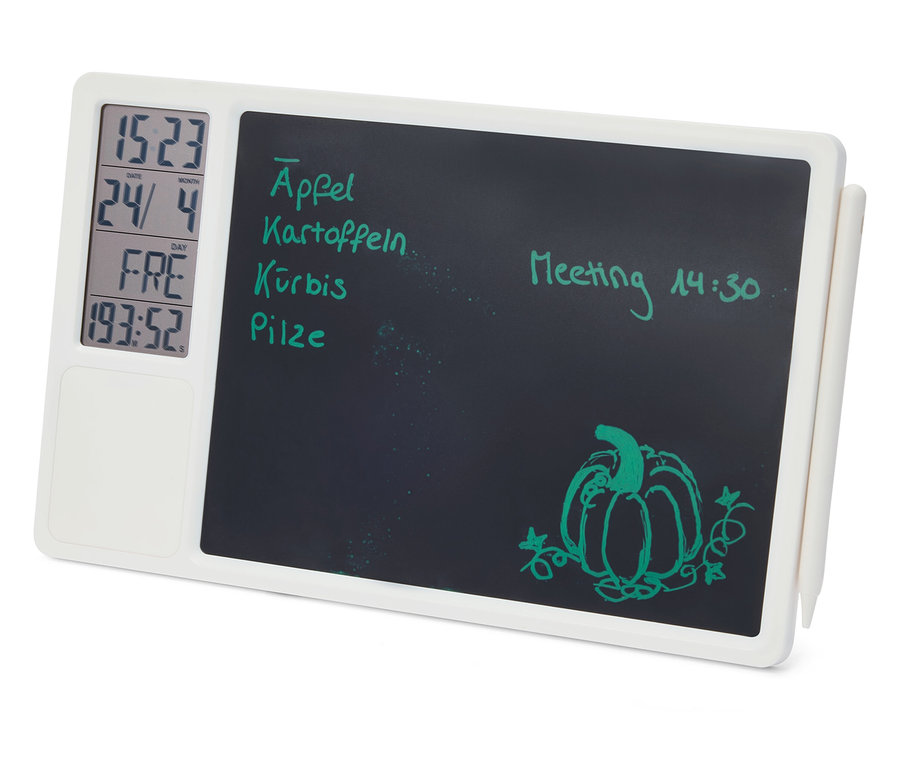 Tableau mémo numérique blanc avec une surface d'écriture noire, affichant à gauche l'heure, la date, le jour et un minuteur. Sur la surface d'écriture, des notes vertes manuscrites comme "Äpfel", "Kartoffeln", "Kürbis", "Pilze" et "Meeting 14:30", ainsi qu'un dessin de citrouille. Un stylet blanc est attaché sur le côté.