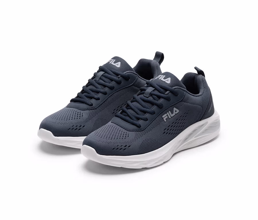 Une paire de chaussures de sport Fila gris foncé avec des semelles blanches et des logos Fila blancs, sur fond blanc.