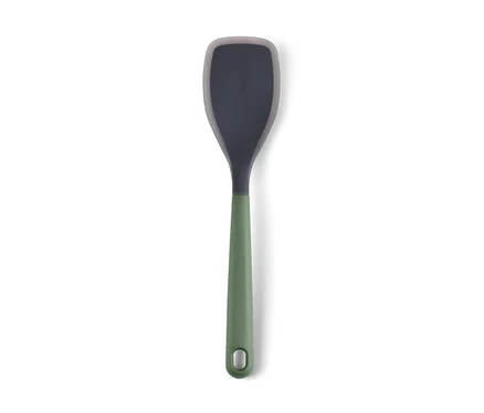 Une spatule de cuisine grise avec un manche vert repose sur un fond blanc.