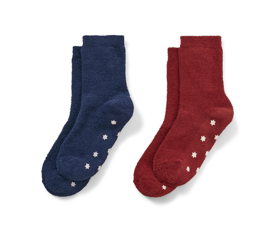 Deux paires de chaussettes moelleuses pour enfant : une paire bleu foncé et une paire rouge, toutes deux avec des étoiles blanches.