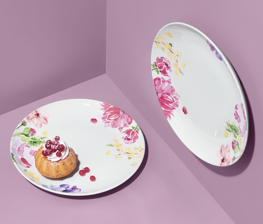 Deux assiettes avec motif floral sur fond violet. Un petit gâteau aux fruits est posé sur une assiette.