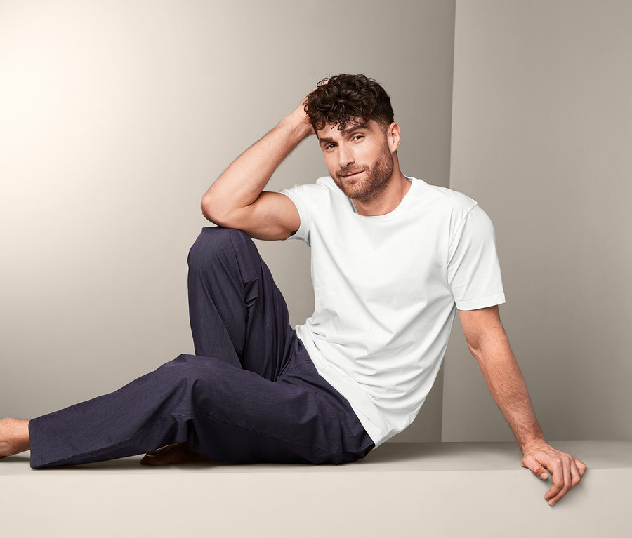 Un homme est assis et porte un t-shirt blanc du lot de 2 t-shirts à encolure ronde.