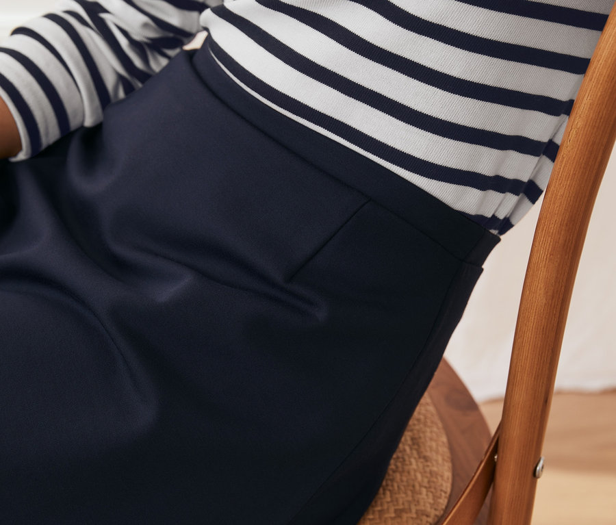 Gros plan d'une femme assise sur une chaise portant une jupe en jersey.