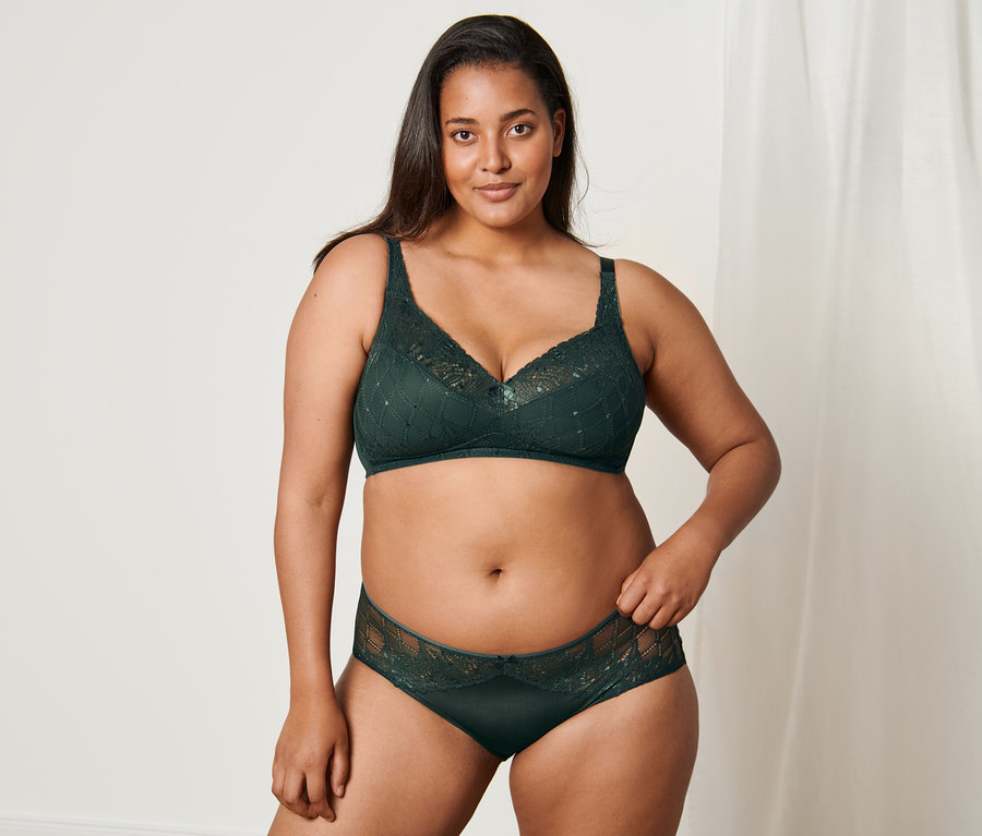 Femme posant dans un ensemble de lingerie vert, comprenant un soutien-gorge doux et une culotte mi-haute.