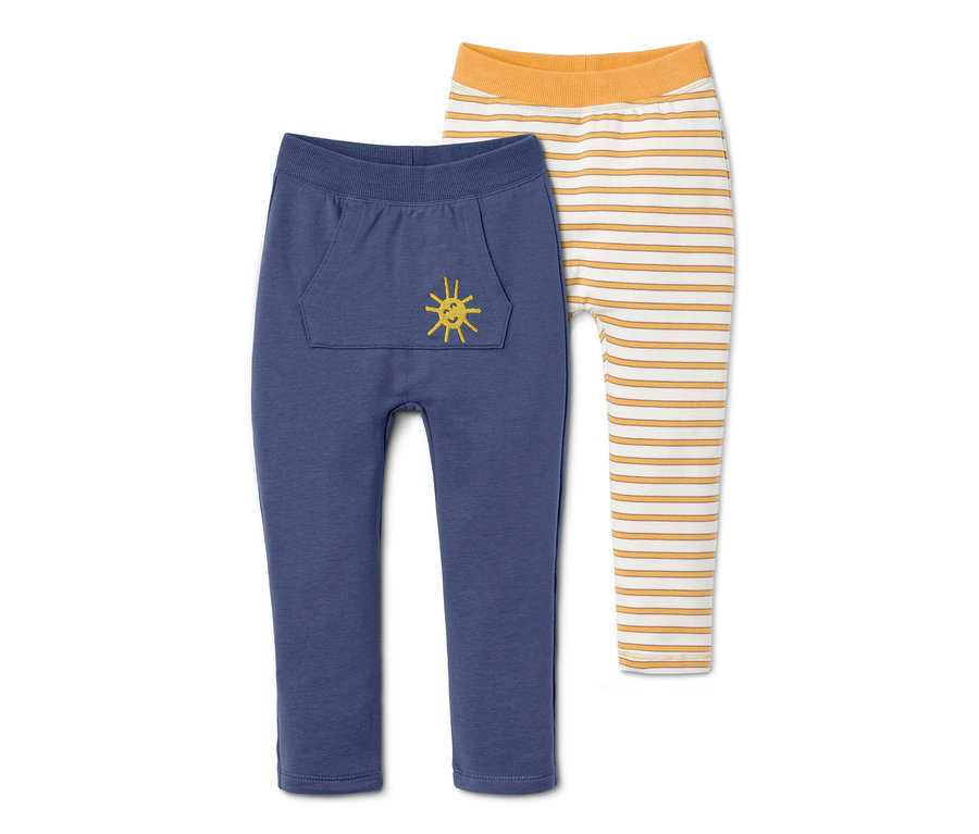 Pantalons molletonnés pour bébés, en coton bio, bleus avec poche et soleil jaune à côté de pantalons molletonnés rayés jaunes et blancs.