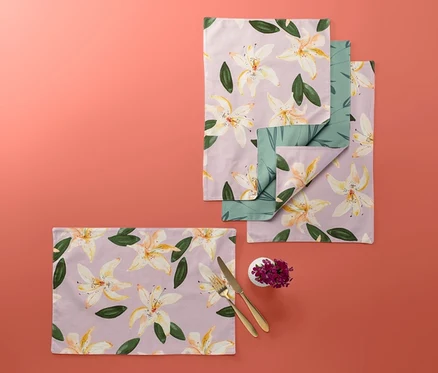 Quatre sets de table réversibles à motif floral sur fond corail.