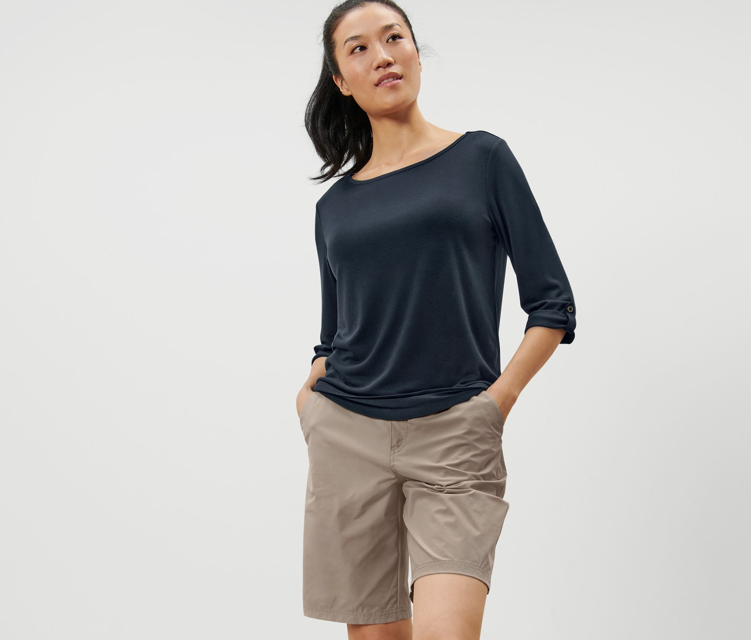 Femme posant dans un t-shirt technique marine à manches 3/4 et un short beige.