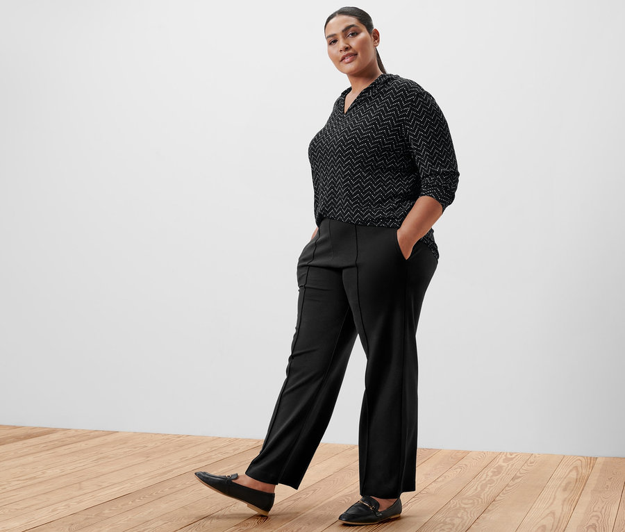 Femme posant en pantalon noir et t-shirt manches longues avec encolure en V, imprimé intégral.