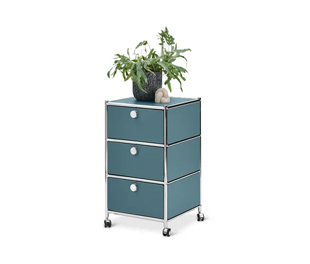 Caisson à roulettes bleu « CN3 » avec 3 tiroirs. Un pot de fleurs et une boule décorative sont posés dessus.