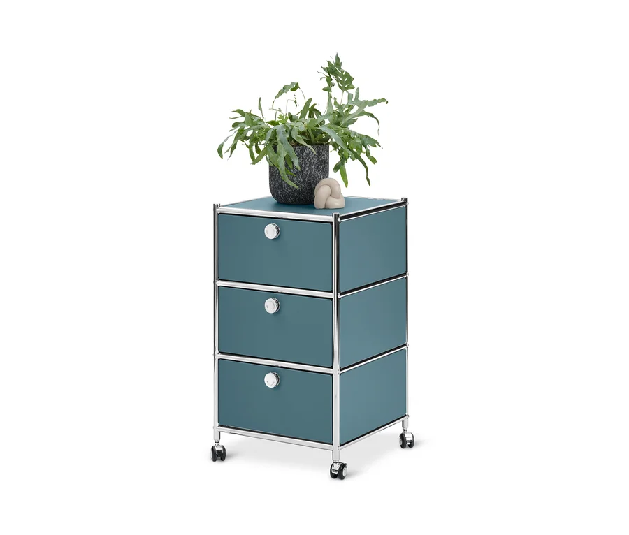 Caisson à roulettes bleu « CN3 » avec 3 tiroirs. Un pot de fleurs et une boule décorative sont posés dessus.