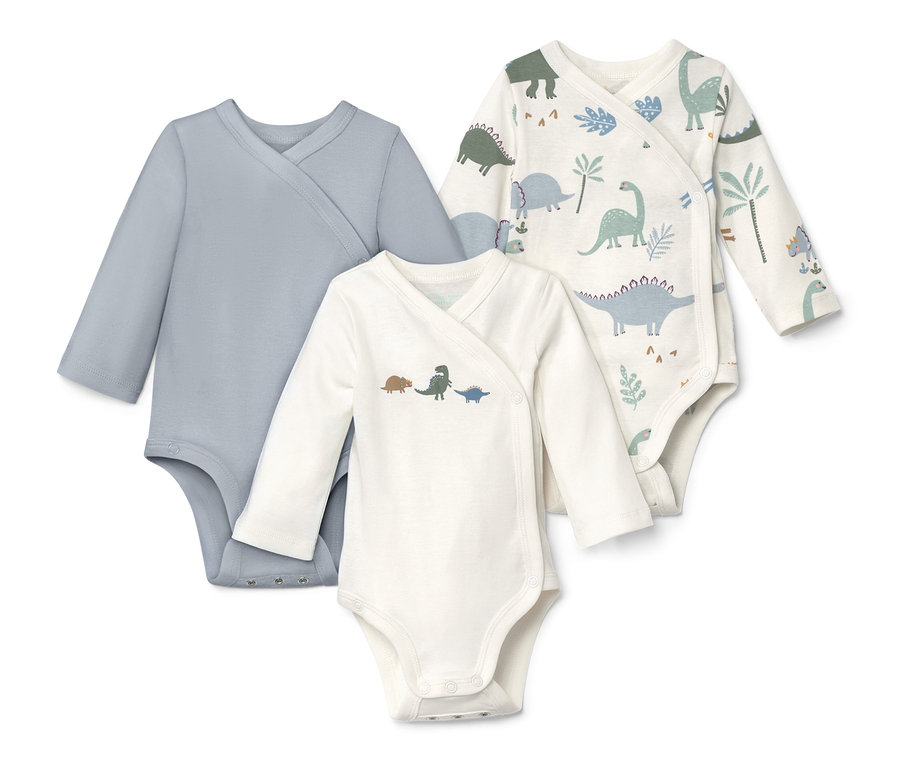 Trois bodys à manches longues, un bleu, un avec des motifs de dinosaures, un avec des motifs de dinosaures et de plantes.