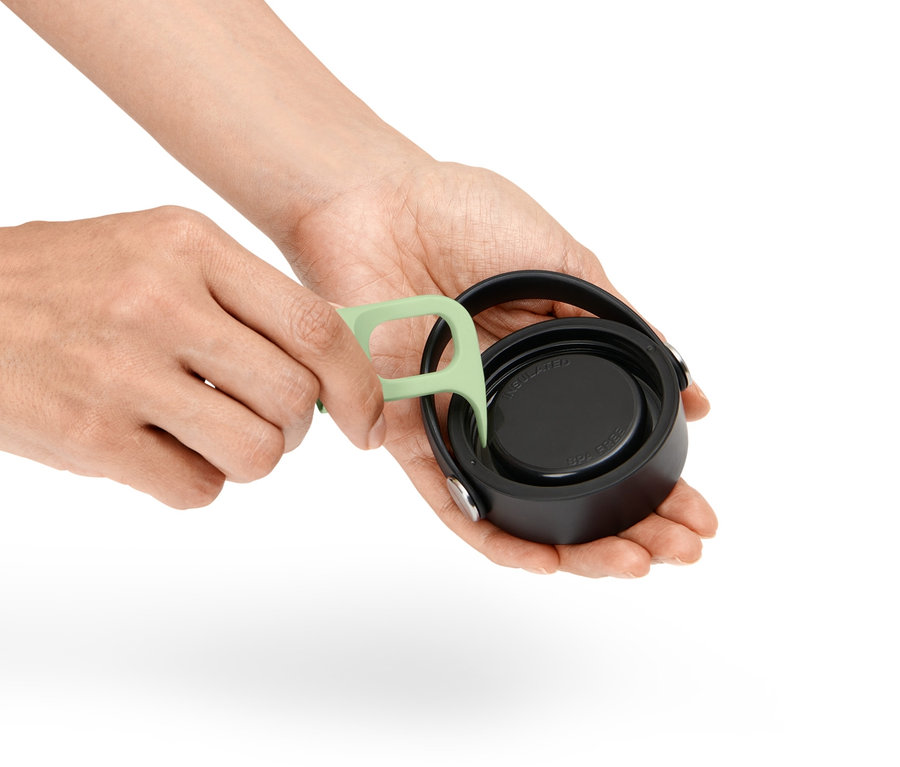 Des mains utilisent un outil vert pour nettoyer les filetages d'un bouchon de bouteille.