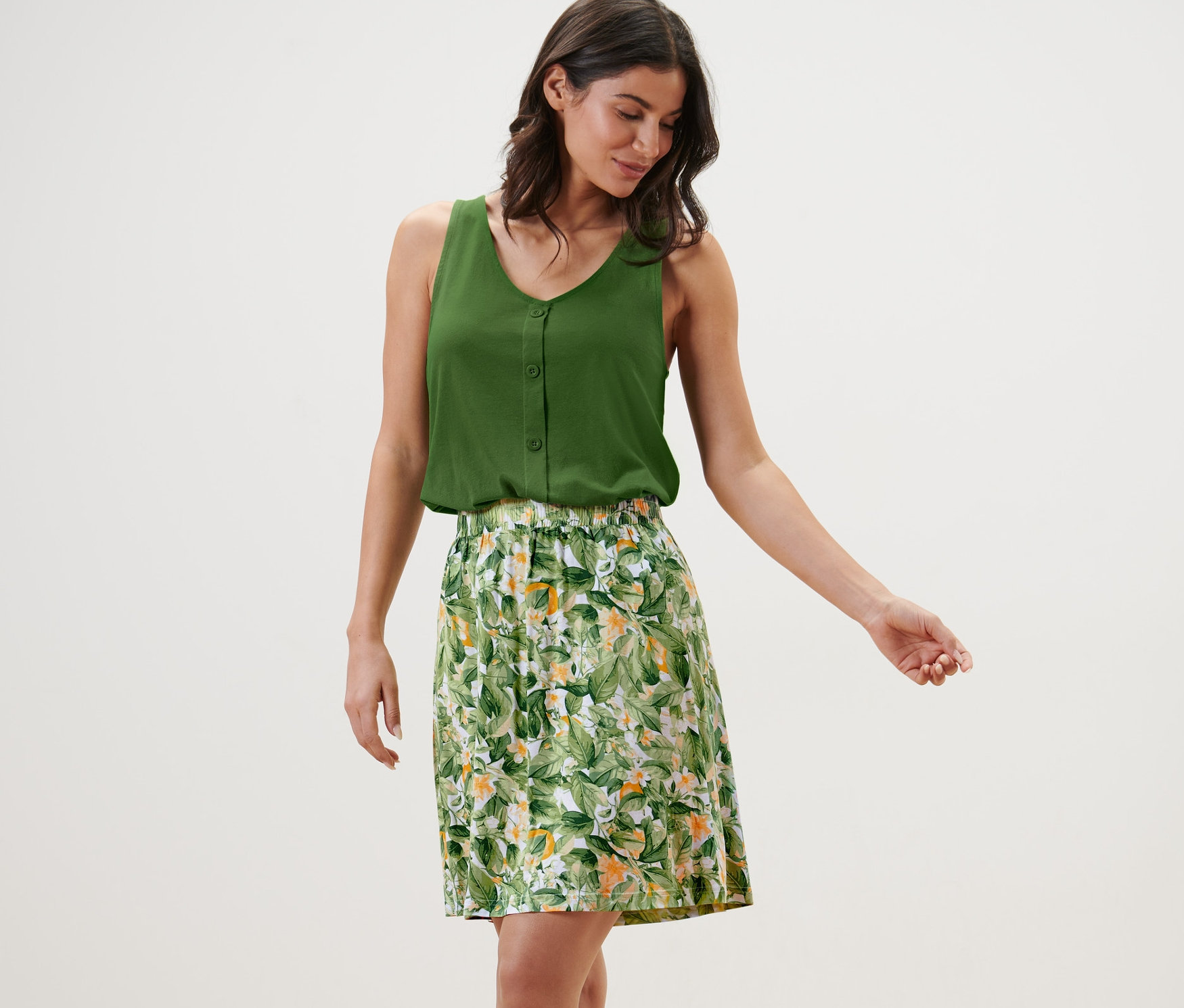 Femme portant un haut vert et une robe en jersey imprimée.