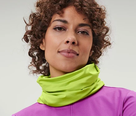 Portrait d'une femme aux cheveux bruns bouclés portant un foulard multifonction jaune autour du cou.